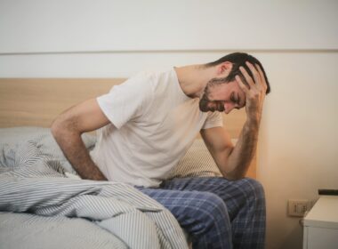 Young man in sleepwear suffering from headache in morning