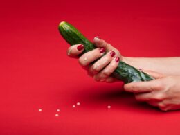 person holding green cucumber on red table