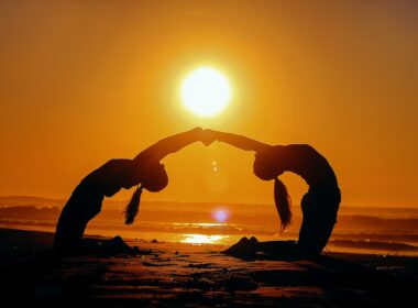 silhouette of two woman bending while holding hands during sunset